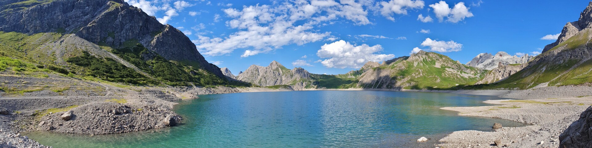 A mountain lake surrounded by rocky terrain and green hills.