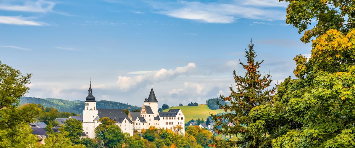 A castle surrounded by lush green trees and a clear blue sky.