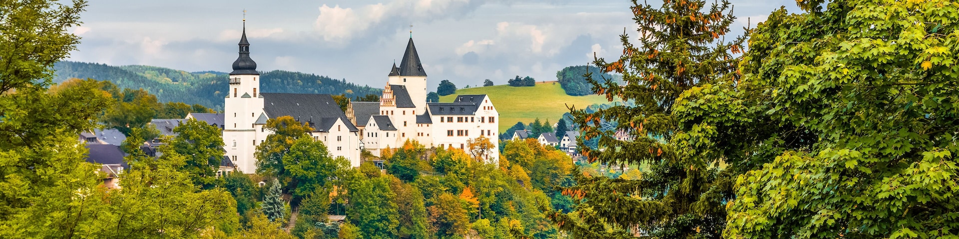 A castle surrounded by lush green trees and a clear blue sky.