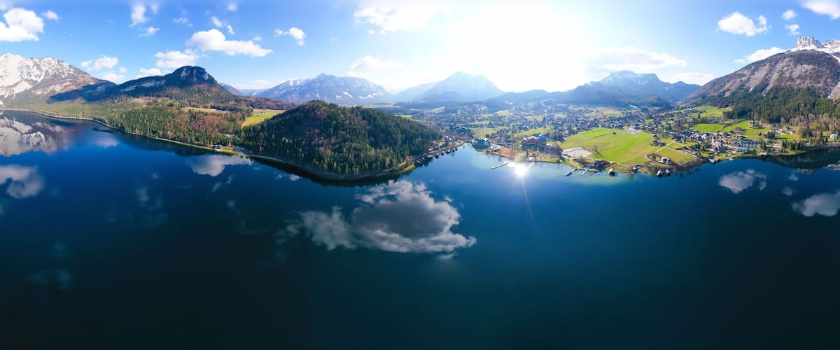 Vista panorámica de un lago rodeado de montañas y un pueblo pequeño.
