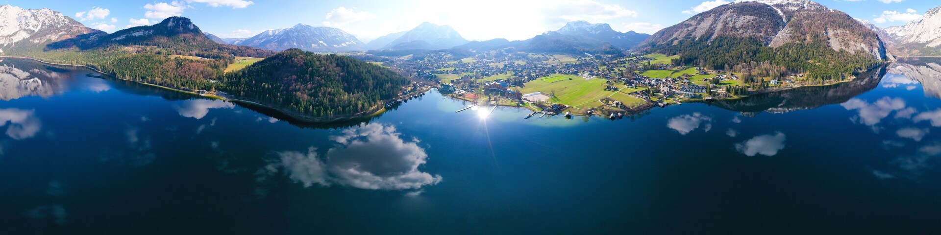 Vista panorámica de un lago rodeado de montañas y un pueblo pequeño.