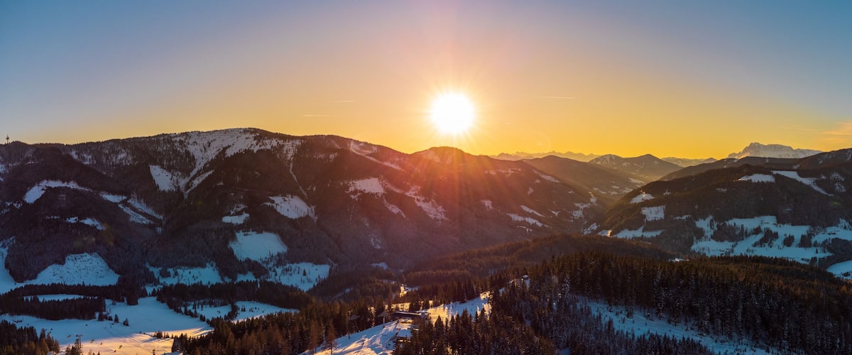A mountain range with a ski resort at sunset.