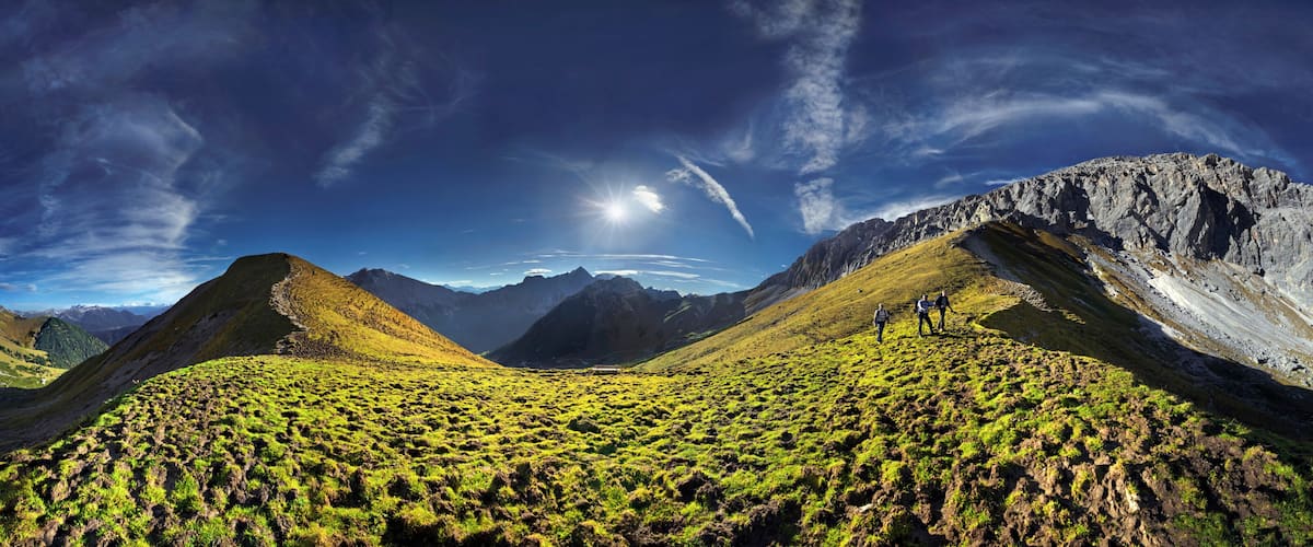 A mountainous landscape with a prominent peak, lush green valleys, and a clear sky.