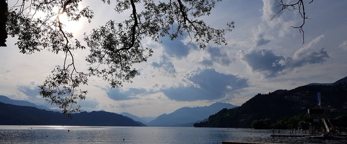 A calm lake with mountains in the background, a clear sky, and a dock with people.