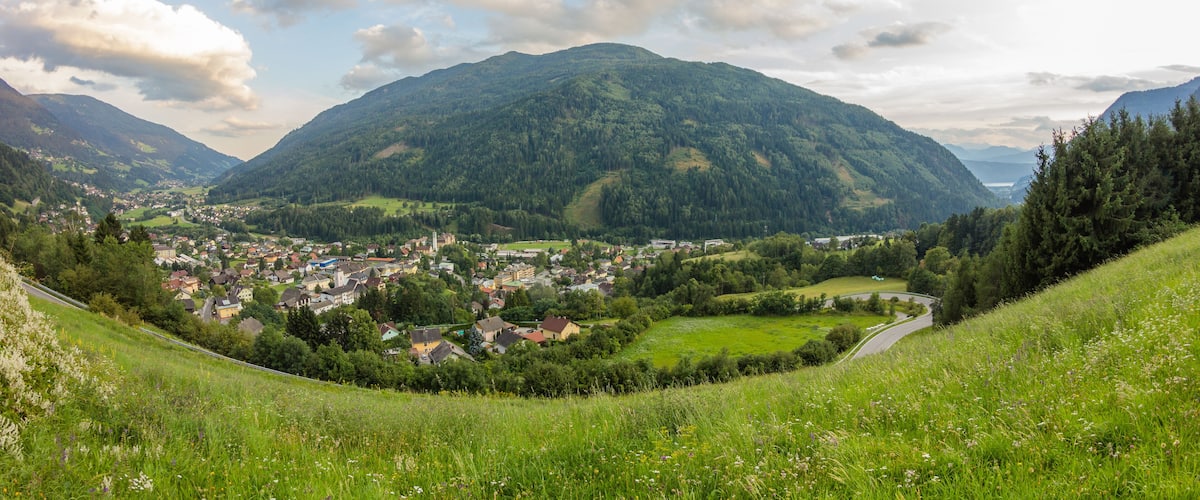 Une vallée où se trouve une ville nichée au milieu de collines verdoyantes, avec une montagne en arrière-plan.
