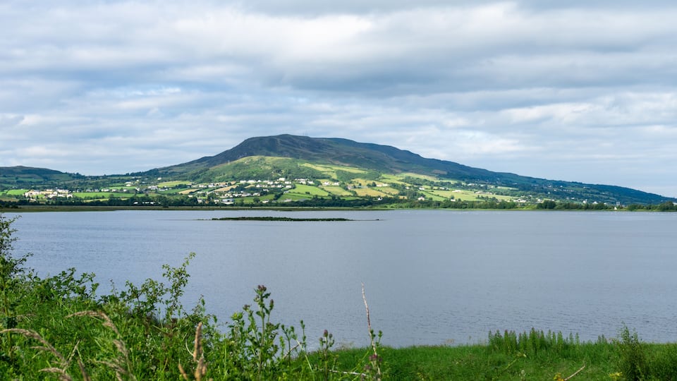 A lake with a mountain in the background and a grassy foreground.