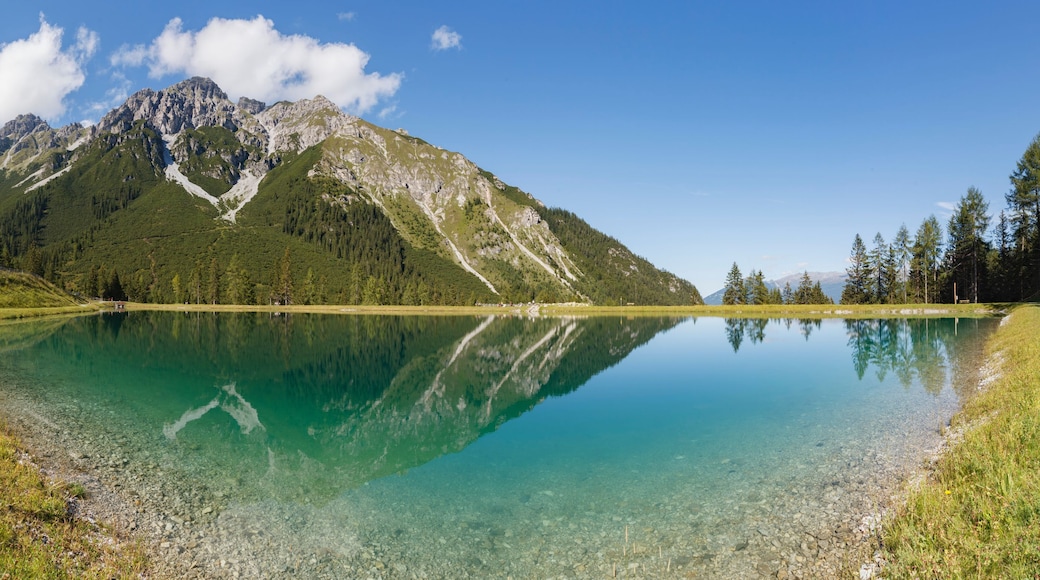 The alpine mountains reflect beautifully in the Panoramasee at Schlick2000 in the Stubai Valley, creating a serene and picturesque scene.