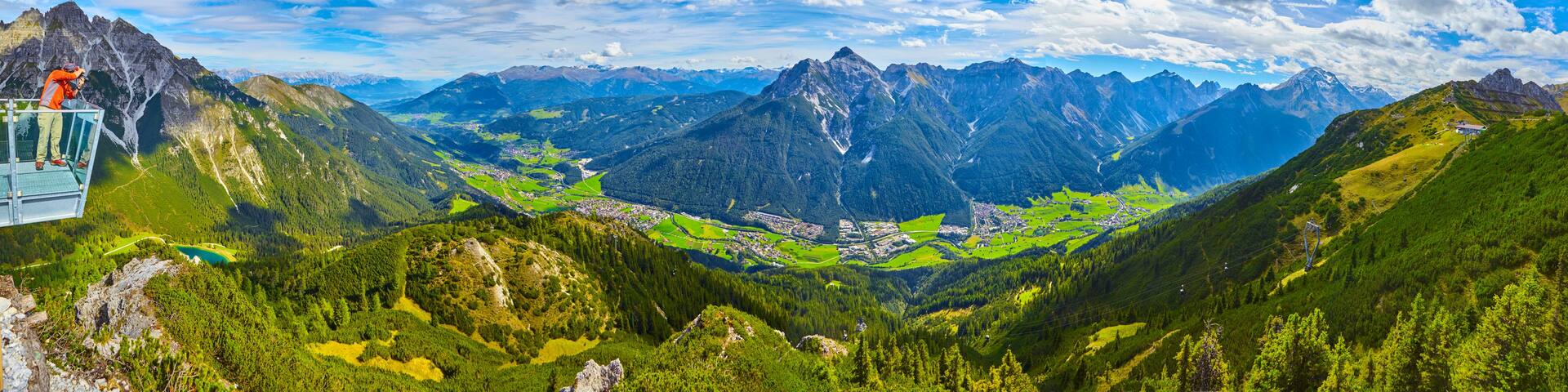 A mountain landscape with a glass bridge, a valley, and a town.