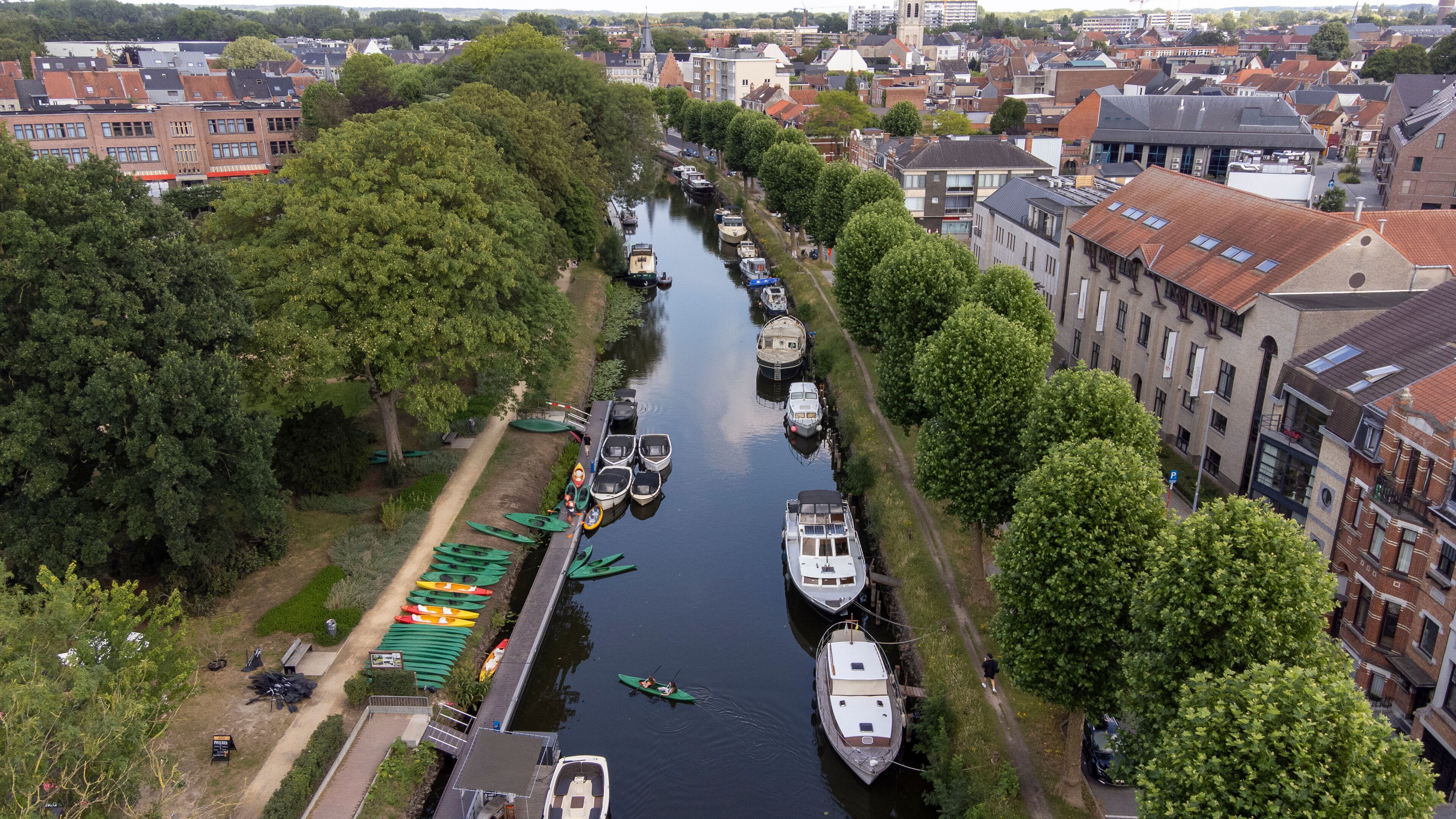 A canal lined with boats and trees, surrounded by buildings.