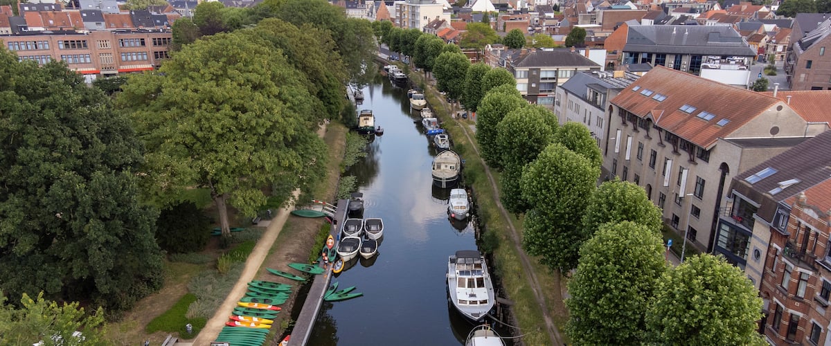A canal lined with boats and trees, surrounded by buildings.