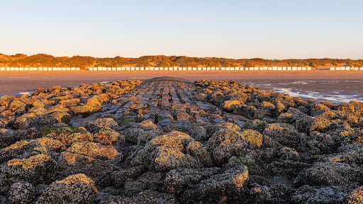 Breakwater with beach cabins panorama at sunset by the North Sea, Bredene, Belgium.