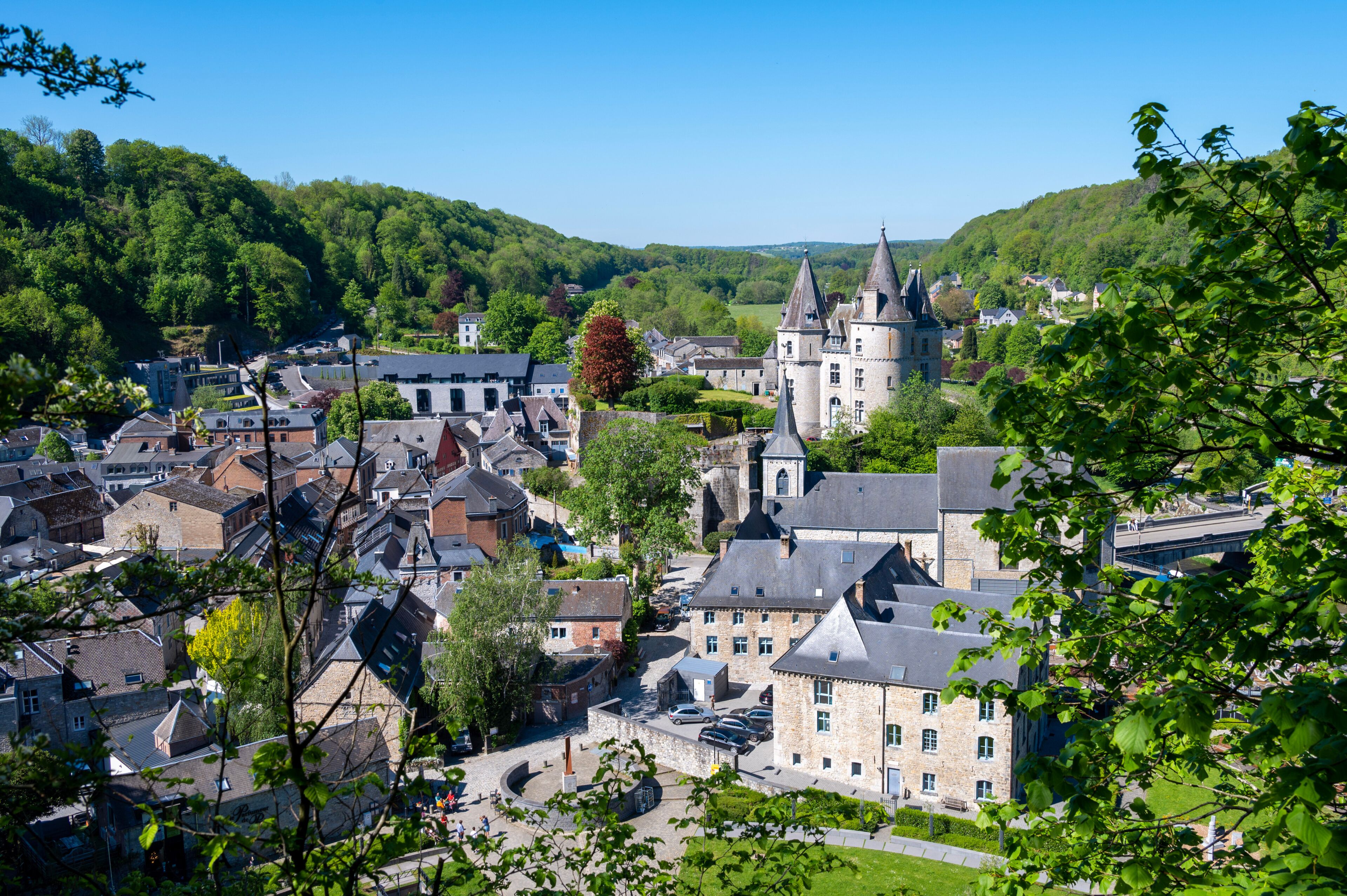 Un pueblo histórico con un castillo imponente, rodeado de exuberante vegetación y arquitectura tradicional.