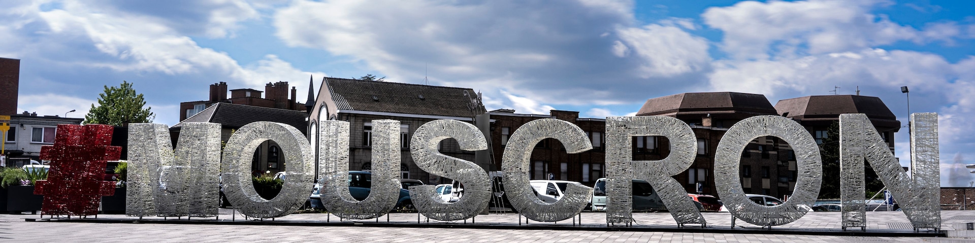 Una gran escultura metálica que deletrea 'HOUSTON' en una plaza abierta con cielo despejado.