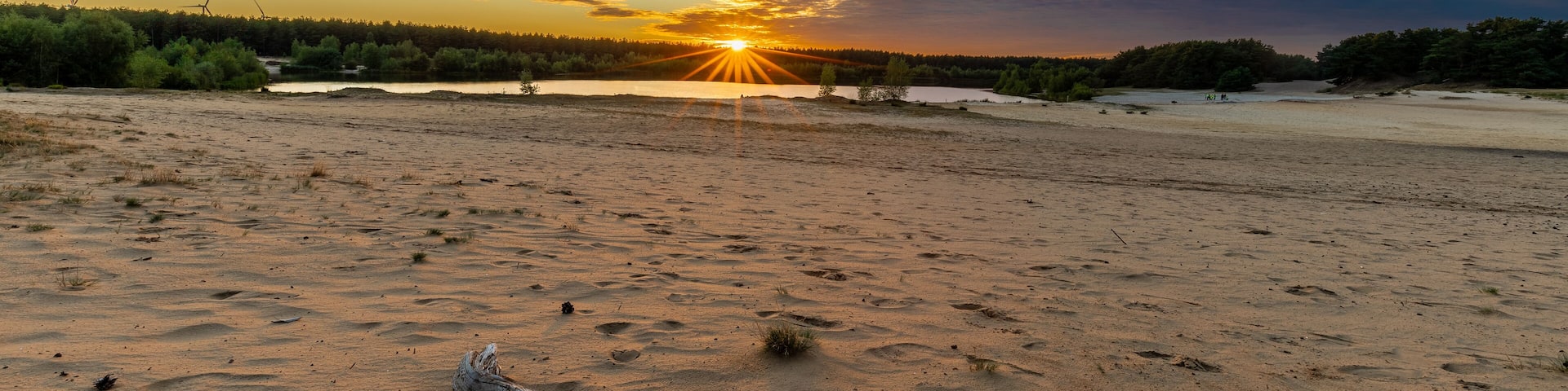 A dramatic and colourful sunset over the Lommelse Sahara, a National Park with sand dunes in Belgium with beautiful reflections in the lake of the clouds and natural colours.