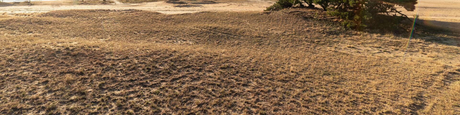 A dramatic and colourful sunset over the Lommelse Sahara, a National Park with sand dunes in Belgium with beautiful reflections in the lake of the clouds and natural colours.