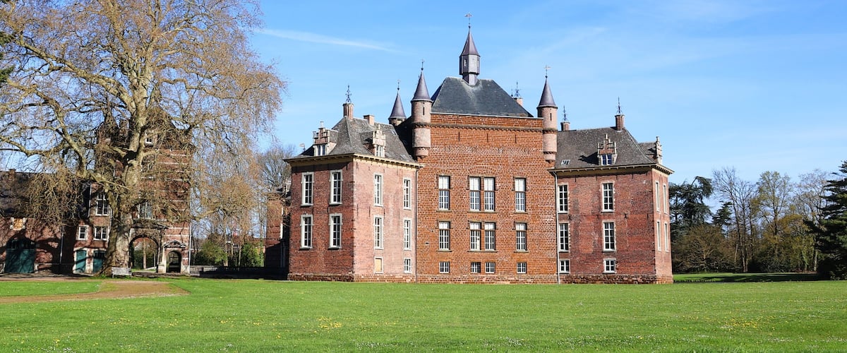 A large, historic brick building with multiple towers and a prominent central tower.