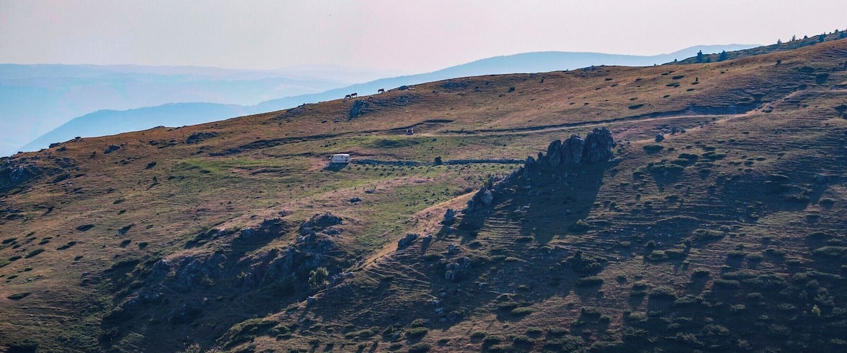 A mountainous landscape with a white building and rocky outcrops.