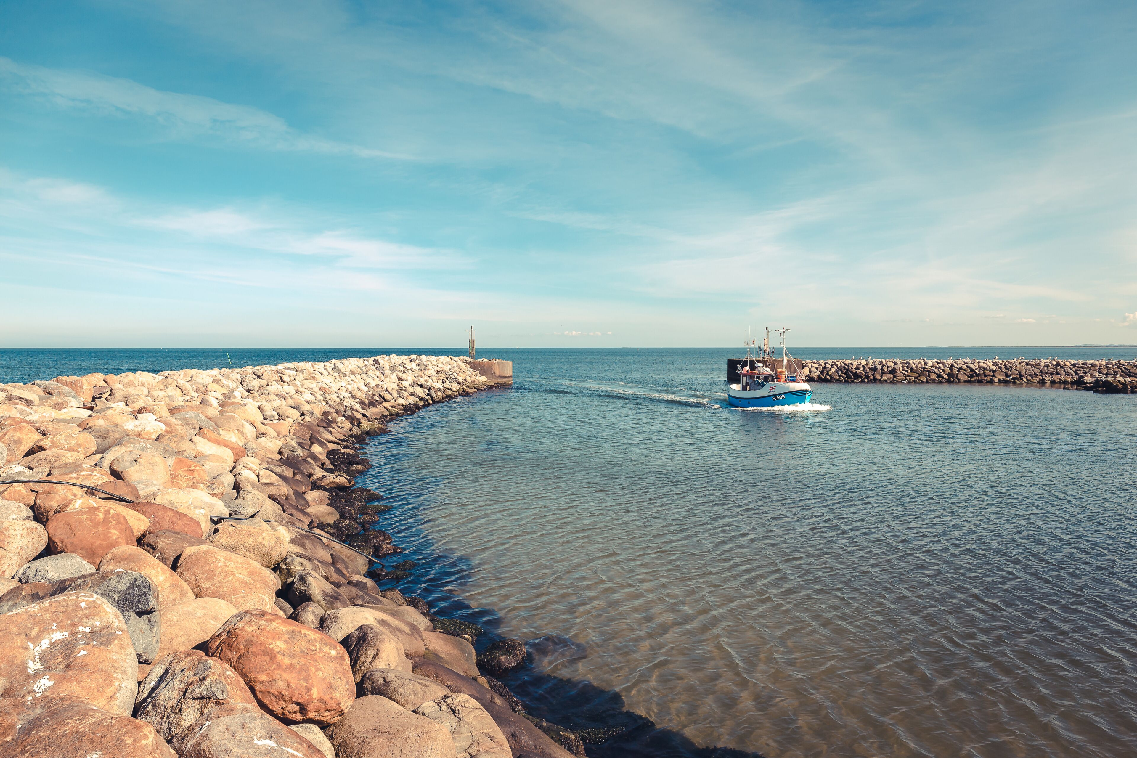 A rocky shoreline with a boat on the water.