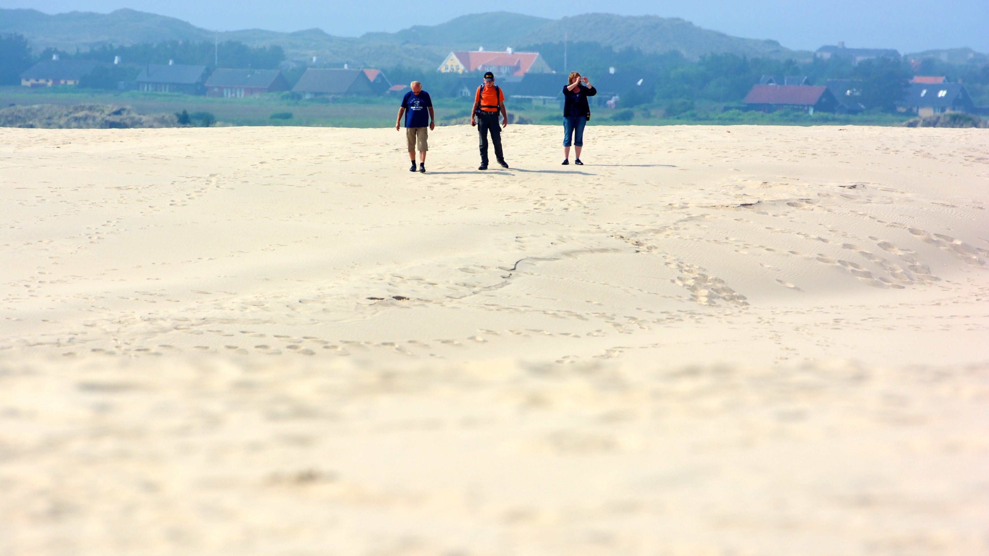 Aalbaek featuring a sandy beach as well as a small group of people