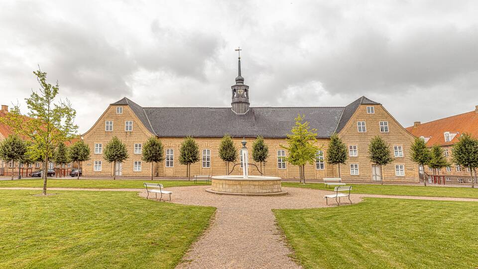 A historic building with a central courtyard, surrounded by trees and benches.