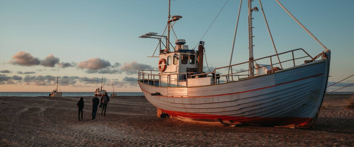 A fishing boat on a sandy beach with a clear sky.