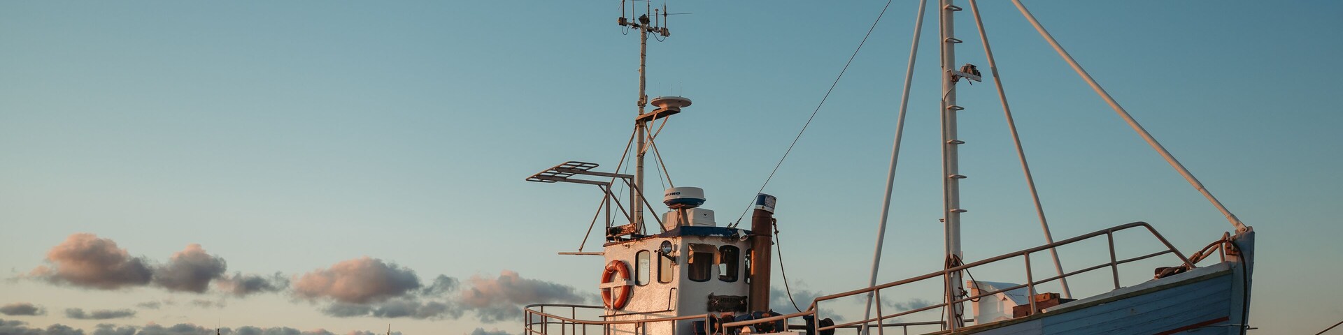 A fishing boat on a sandy beach with a clear sky.