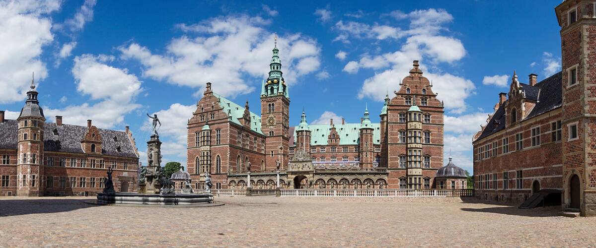 A historic building with a large courtyard, a fountain, and a clock tower.