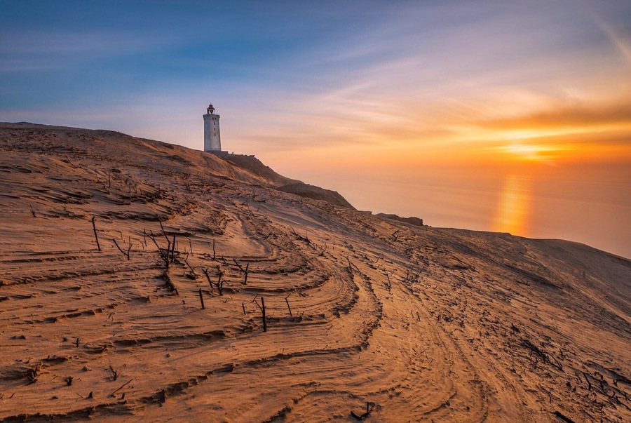 An old lighthouse build in 1900 and placed on a cliff 60m above sea level.
Over time, the lighthouse has been swallowed by the sand dunes, which make a a very unique place to visit. This is a must to visit if you're in Denmark/Jutland.
There is a parking lot 1 km- ish from the lighthouse and a great walk path right from the parking lot to the lighthouse.