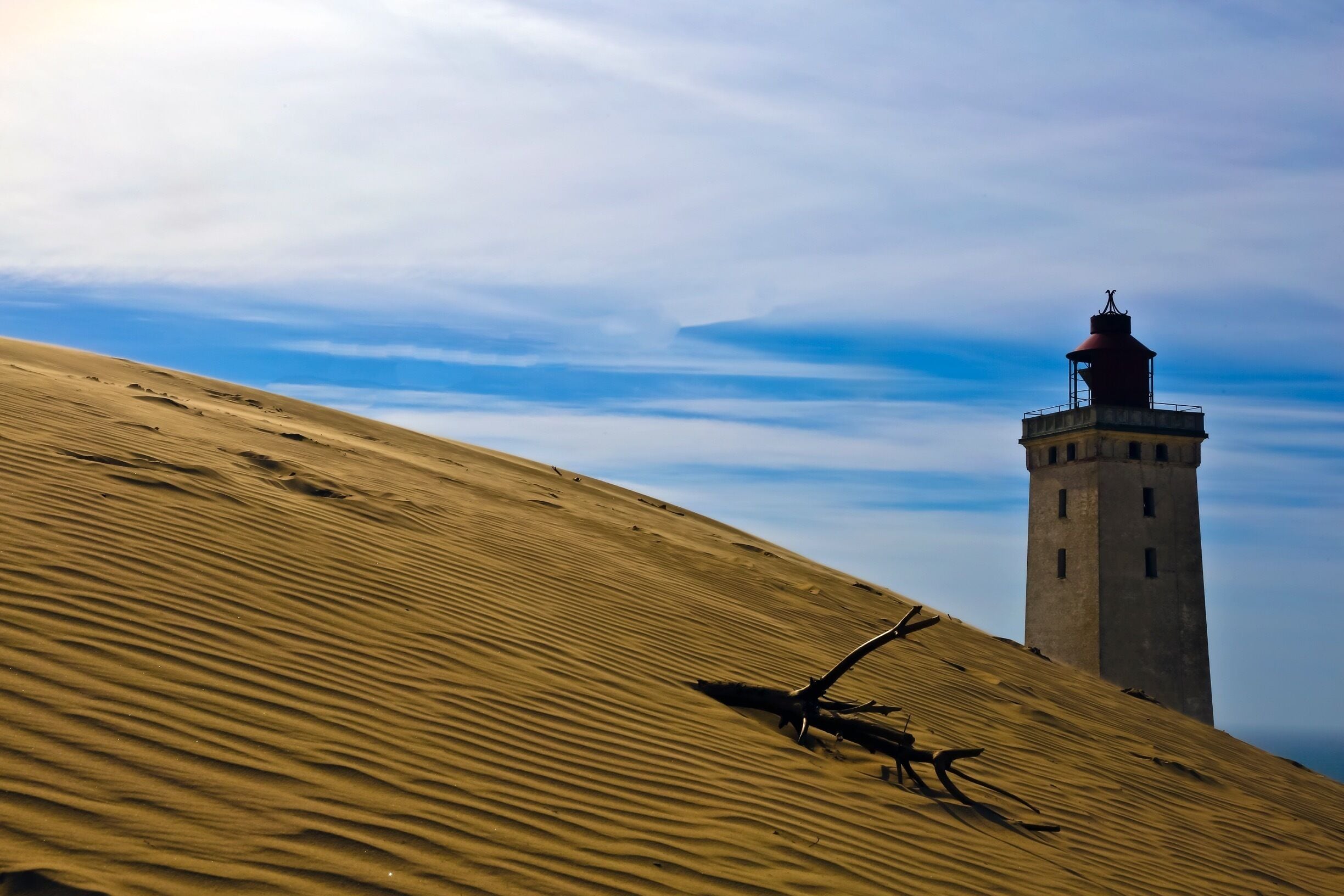 Welcome to Denmark !!

This is Rubjerg Knudle Lighthouse near Aalborg on the Northwestern coast of the North Sea.  It was first lite in 1900 and was functional to 1969.
The interior (somewhat unsafe brick and stairs) will be closed in a year and the entire structure is expected to be swallowed by the sea within 10 years. It was officially closed as  a Lighthouse in 1969 and later in 1980 re opened as a giant Kaleidoscope.  
The 3 supporting houses next to the lighthouse have already been destroyed by the encroaching sea and deepening sand dunes. 
This will be a casually of global warming and the encroachment of the sea. 