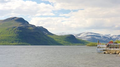A lake with mountains in the background and a boat on the shore.