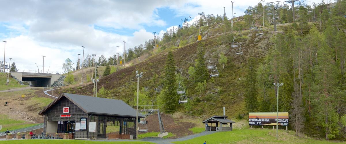 A ski lift, a small cabin, a sign, and a body of water.