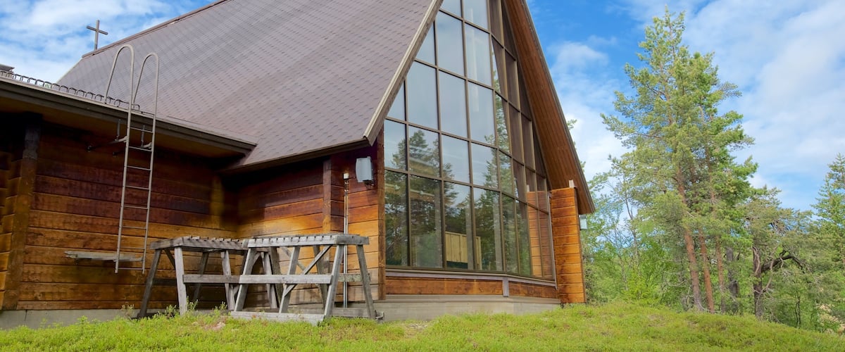 A wooden cabin with a large glass window and a metal ladder.