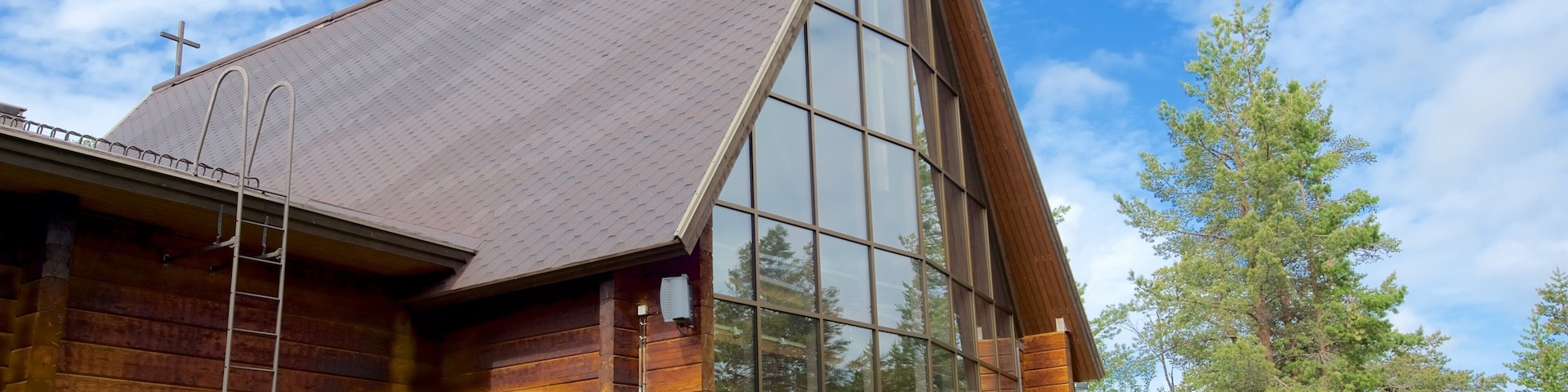 A wooden cabin with a large glass window and a metal ladder.