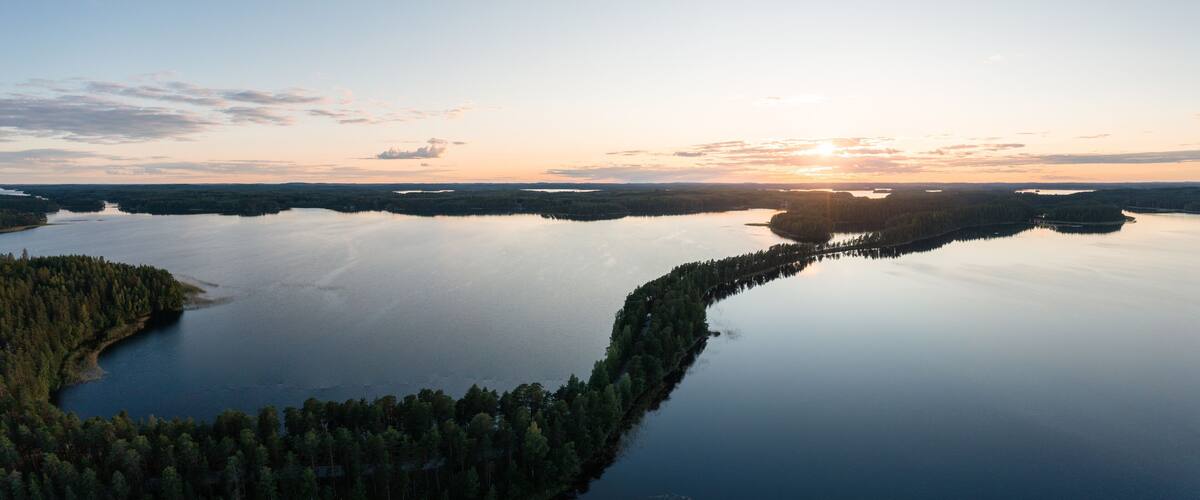 A serene lake surrounded by dense forests at sunset.
