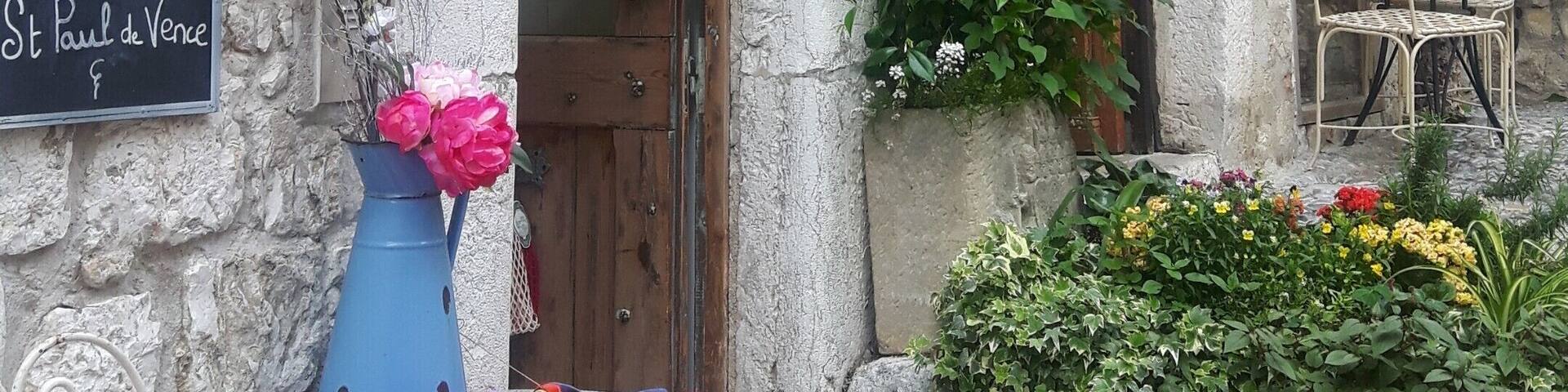 A stone building with a sign reading "GODET" and a chalkboard sign advertising "ICI ATELIER CREATION."