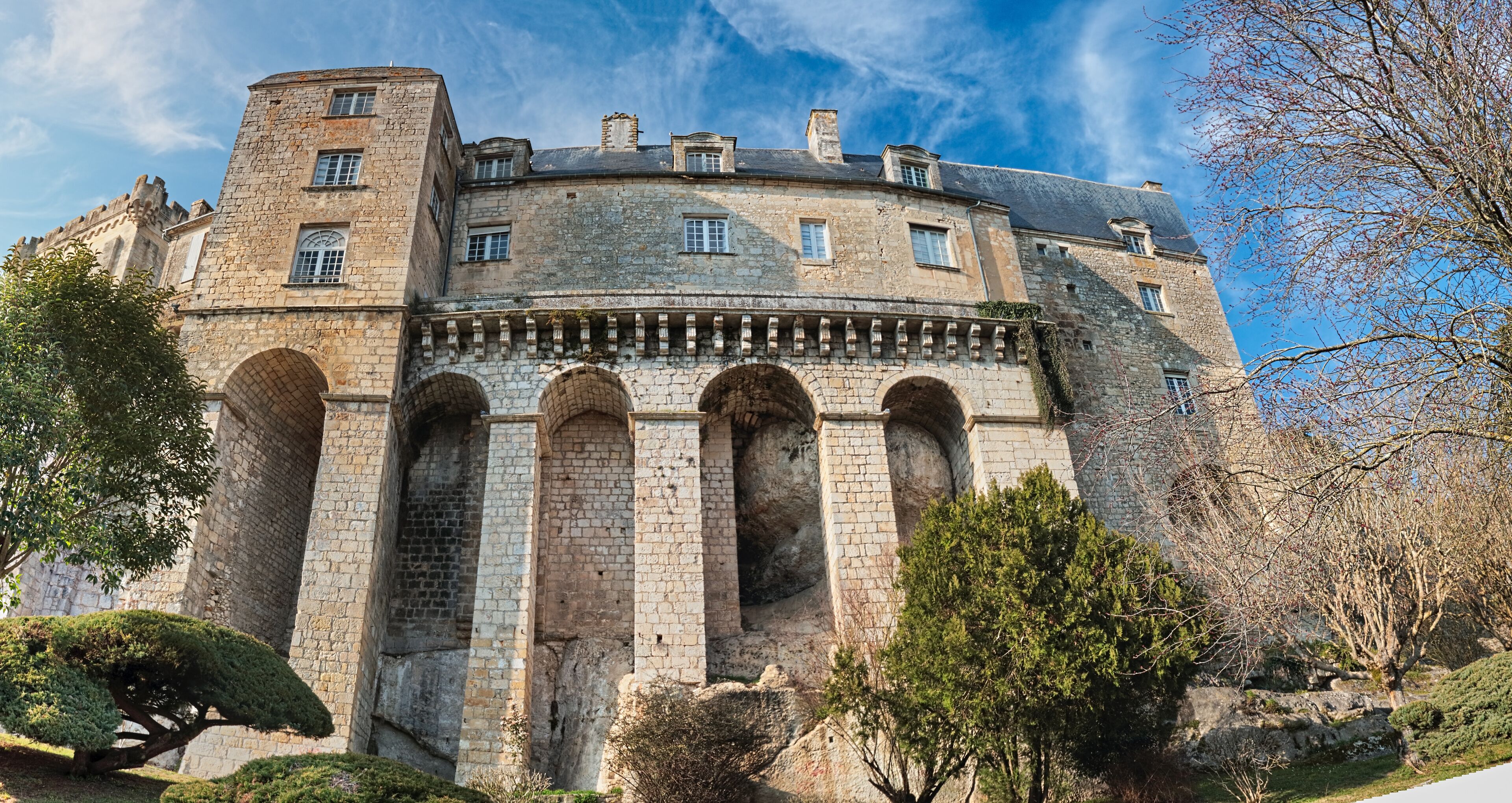 Un castillo histórico de piedra con ventanas de arco y una torre.