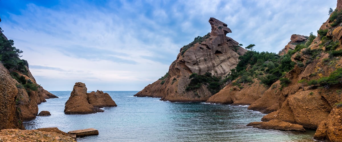 Un paisaje costero con acantilados rocosos, un mar tranquilo y un cielo despejado.