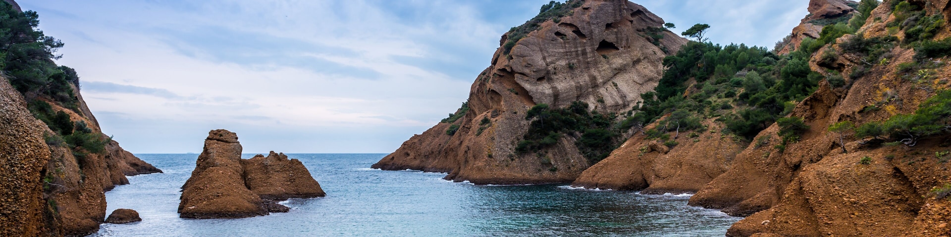 Un paisaje costero con acantilados rocosos, un mar tranquilo y un cielo despejado.