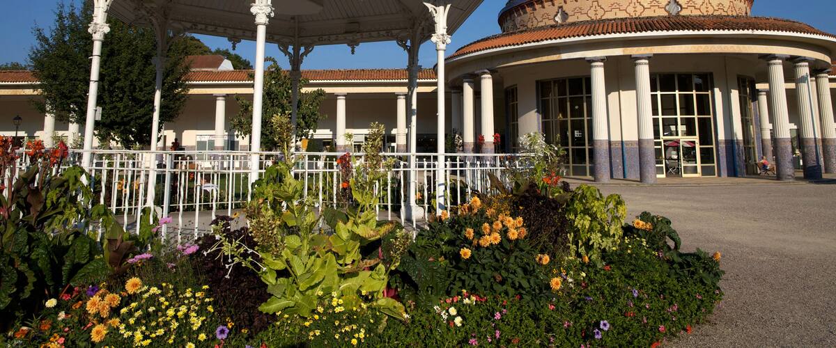 A gazebo with a dome and columns, surrounded by a garden with various flowers.