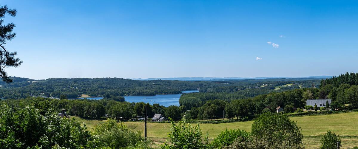 A lake surrounded by forested hills and a few houses.