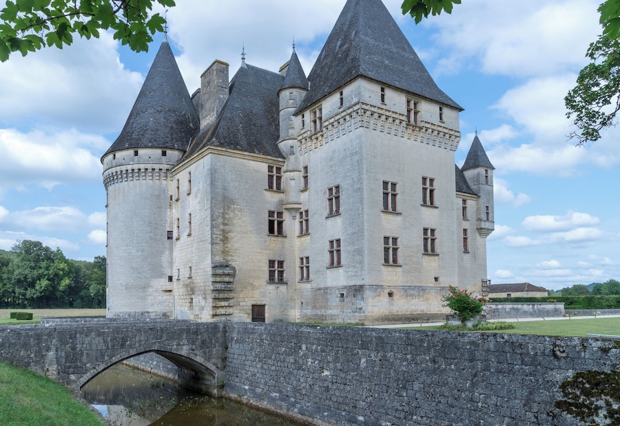 A historic castle with multiple towers, a stone bridge, and a moat.