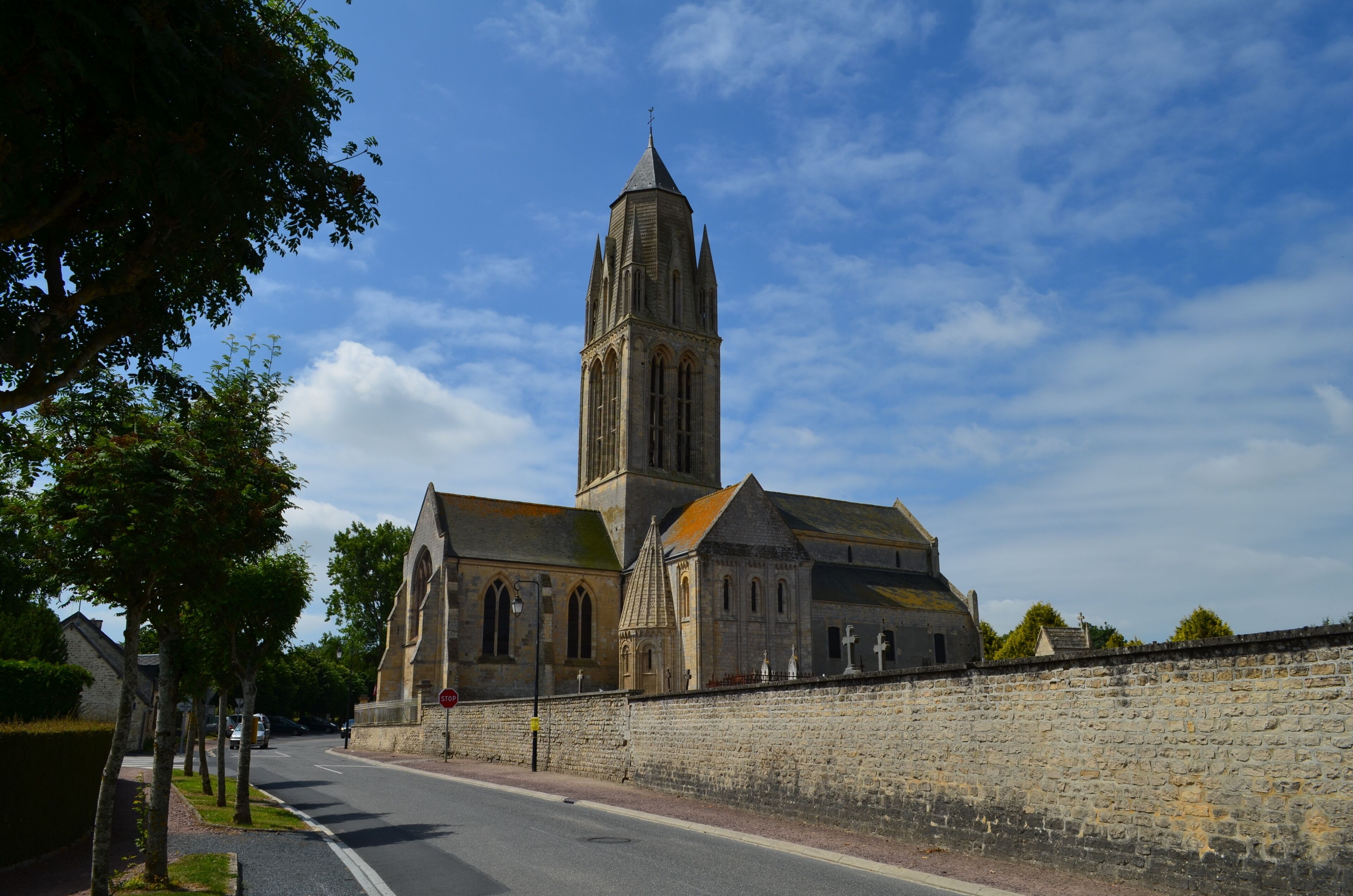 A historic church with a tall tower and a stone wall in the foreground.