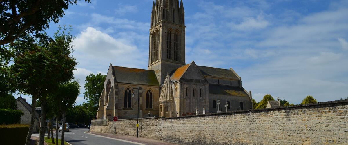 A historic church with a tall tower and a stone wall in the foreground.
