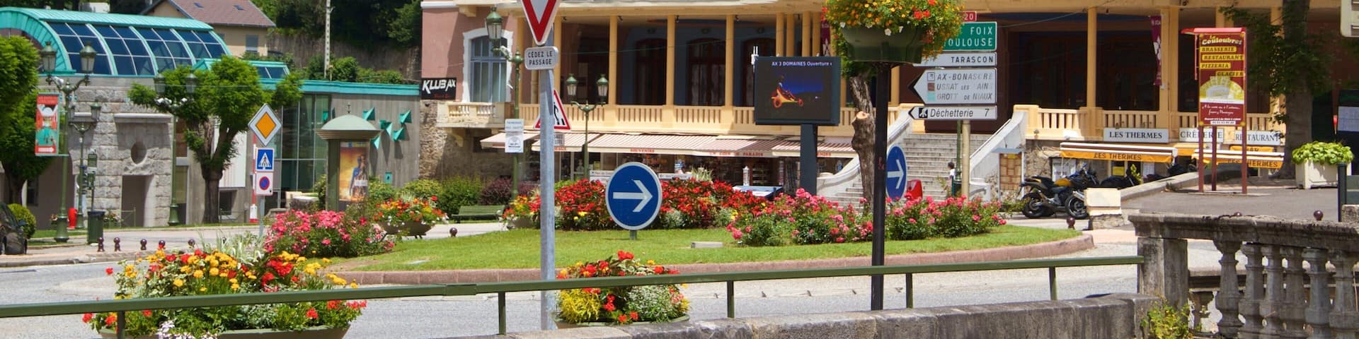 A town square with a casino, a bar, and a cinema. There are flower beds and a traffic sign.