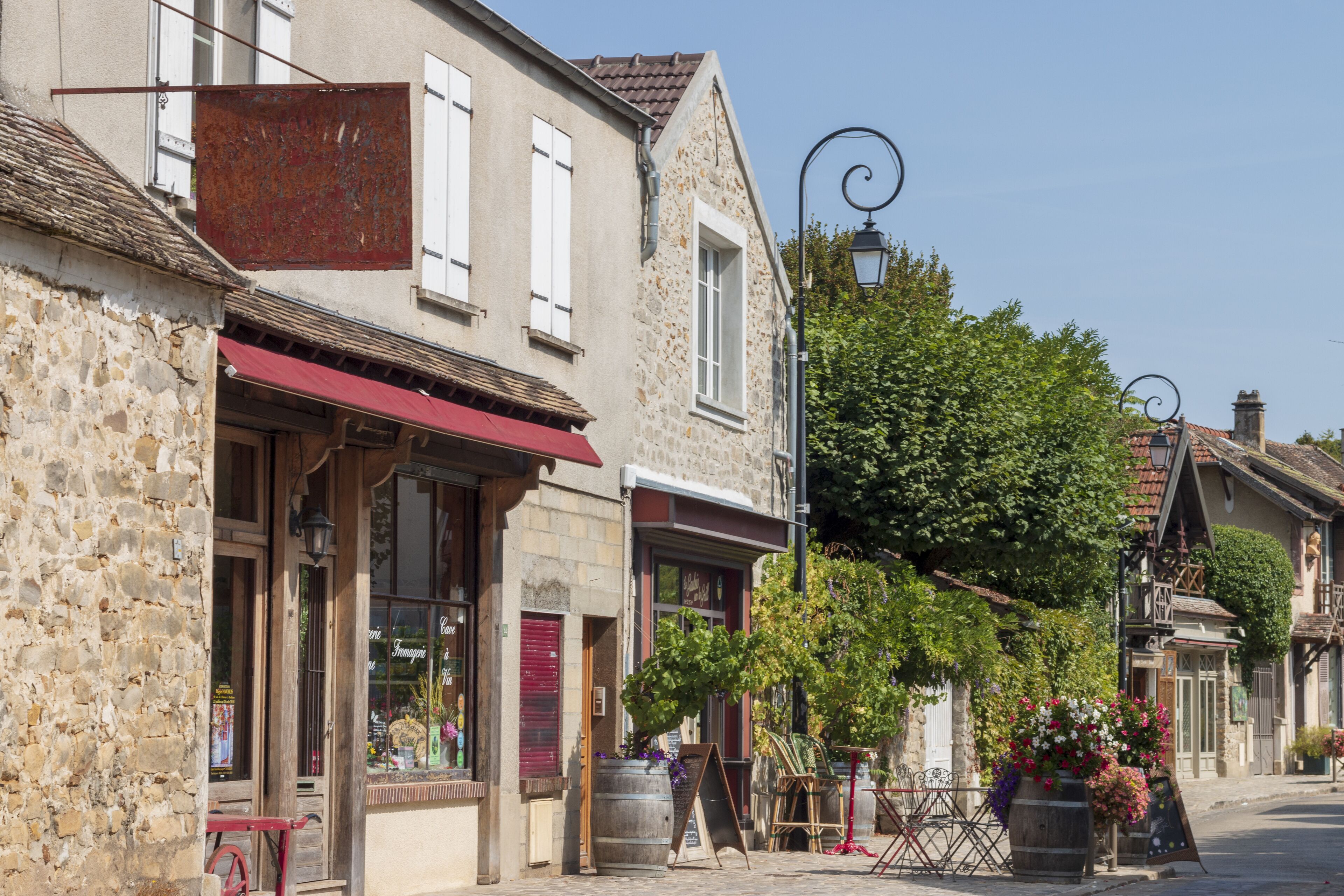 A cobblestone street with stone buildings, a red awning, and a signboard.