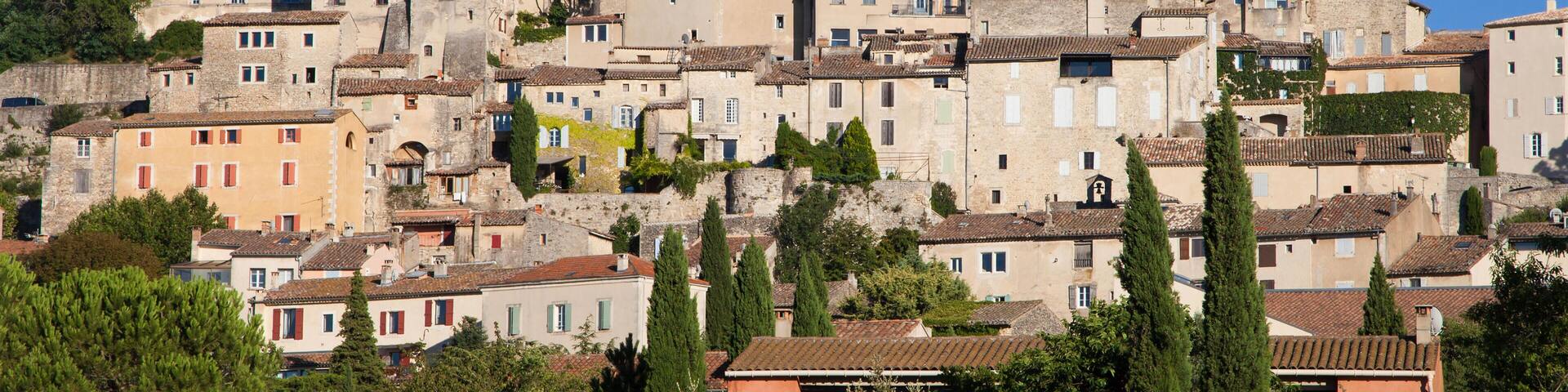 A historic town with a prominent church tower, terracotta-roofed buildings, and lush greenery.