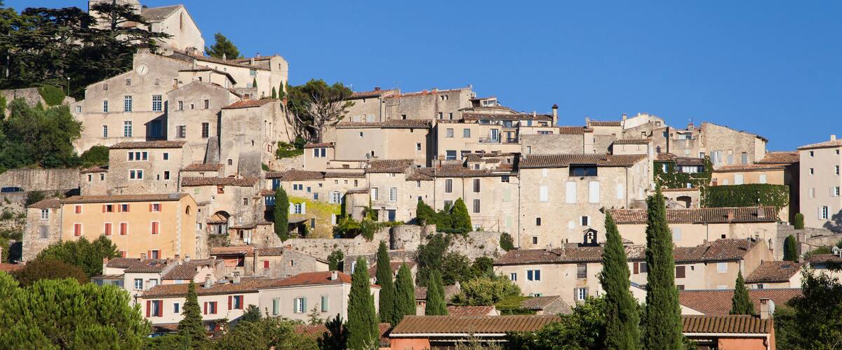 A historic town with a prominent church tower, terraced buildings, and lush greenery.
