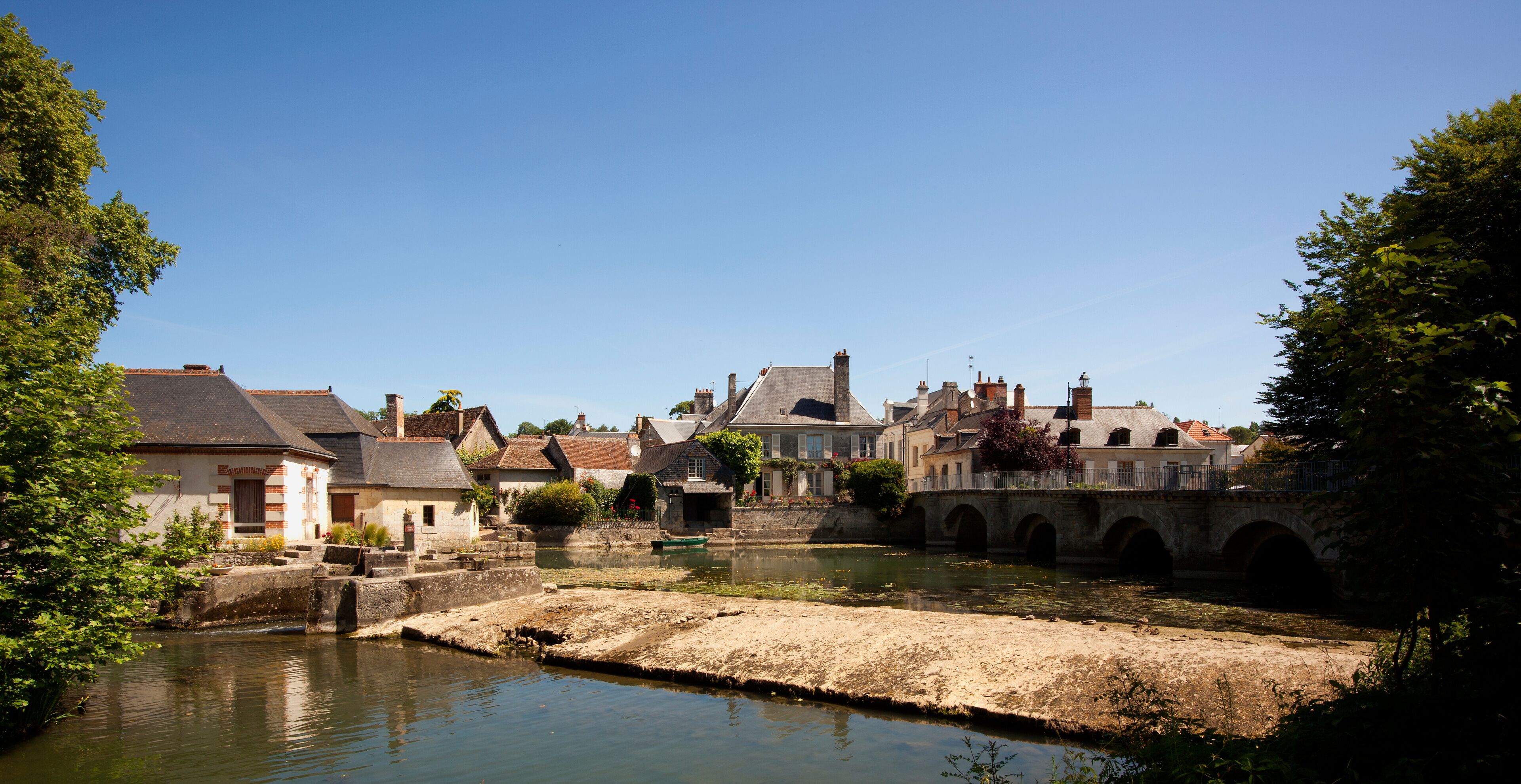A riverside town with historic buildings, a bridge, and a canal.