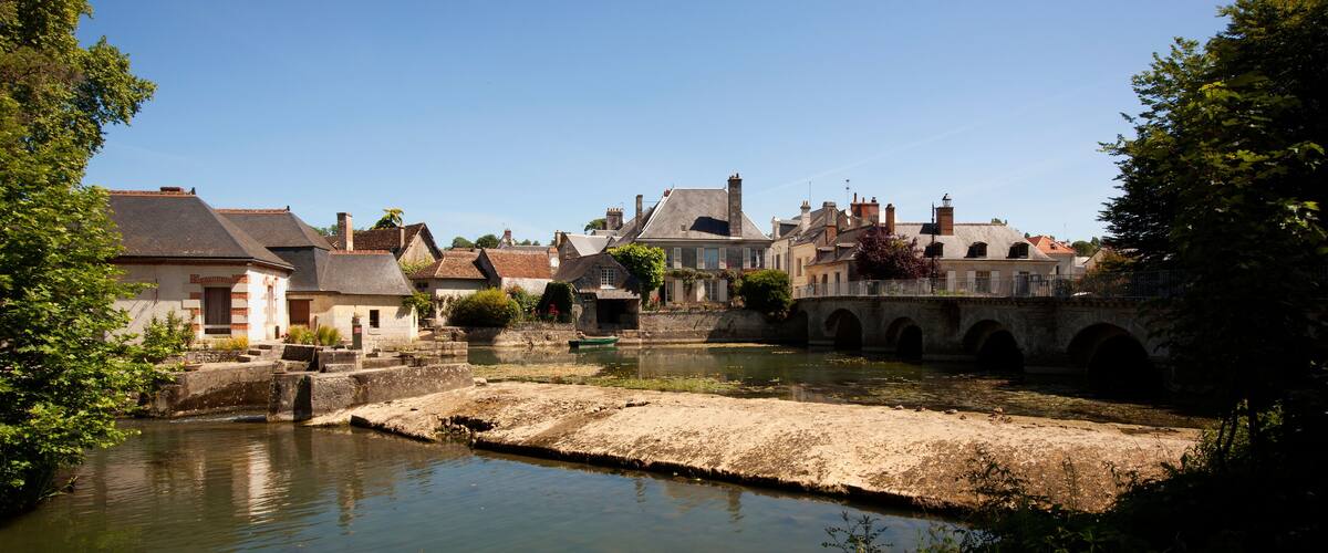 A riverside town with historic buildings, a bridge, and a canal.