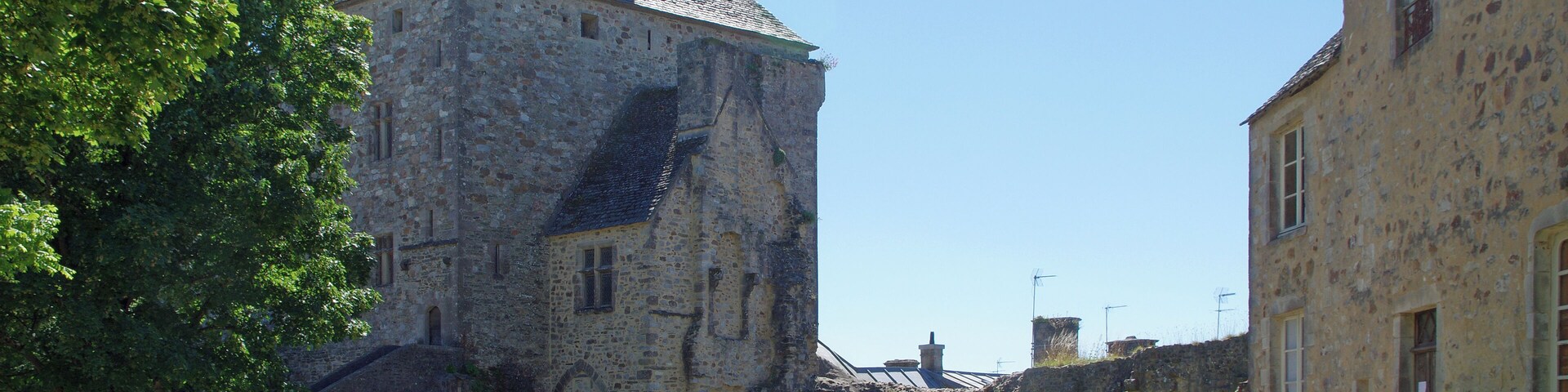 Bricquebec-en-Cotentin (Manche). Le château (La cour intérieur) La Tour de l'Horloge : Enorme tour rectangulaire avec son clocheton, c'est le châtelet d'entrée. La tour est percée de deux portes, une porte piétonne et une porte charretière. Le châtelet est construit en schiste pour la partie basse et en grès pour les étages. Les entourages de fenêtres sont en calcaire. On accède aux étages par un escalier externe côté cour. La Pyramide de mémoire : Pyramide création de l'architecte-designer Pascal Morabito pour célébrer le passage à l'an 2000. La Pyramide de mémoire contient 2000 objets du souvenir dons des Bricquebétais, douilles, briquets, casques, éclats d'obus, etc. Ces objets sont emprisonnés dans un mortie composé avec du sable des plages du débarquement de la Seconde Guerre mondiale. L'érosion laissera réapparaître les objets aux générations futures. Une partie du chartrier : Bâtiment où étaient conservés les chartes, les titres prouvant les droits seigneuriaux.